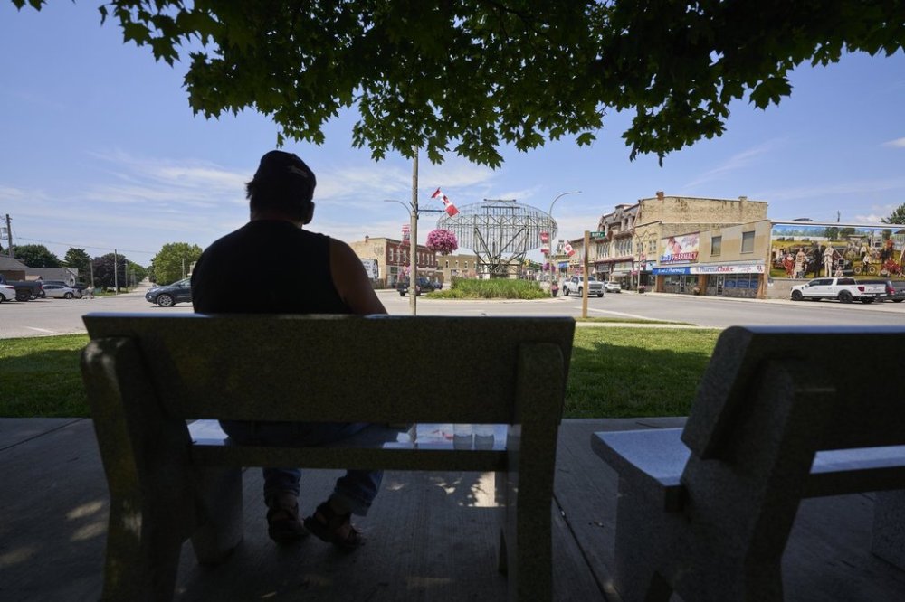 A man sits on a bench in a park in downtown Clinton, Ont., Monday, July 8, 2024. THE CANADIAN PRESS/Geoff Robins