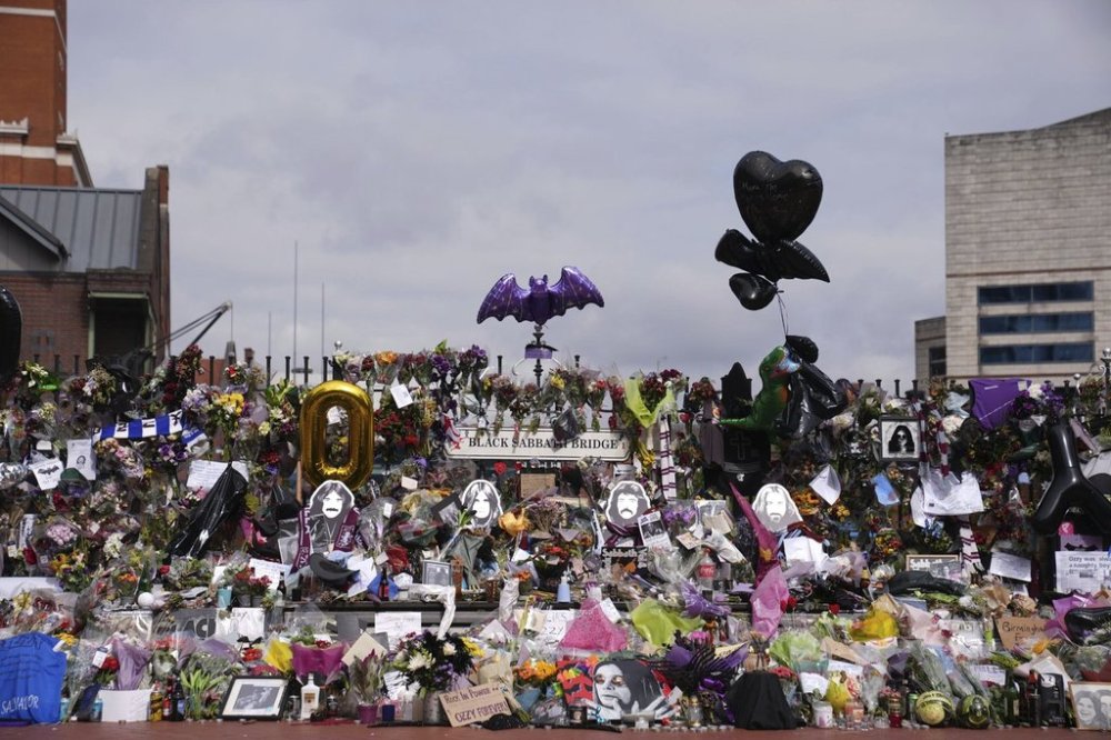 Floral tributes left at the Black Sabbath Bridge bench on Broad Street in memory of Black Sabbath frontman Ozzy Osbourne ahead of the funeral procession, in Birmingham, England, Wednesday July 30, 2025. (Joe Giddens/PA via AP)