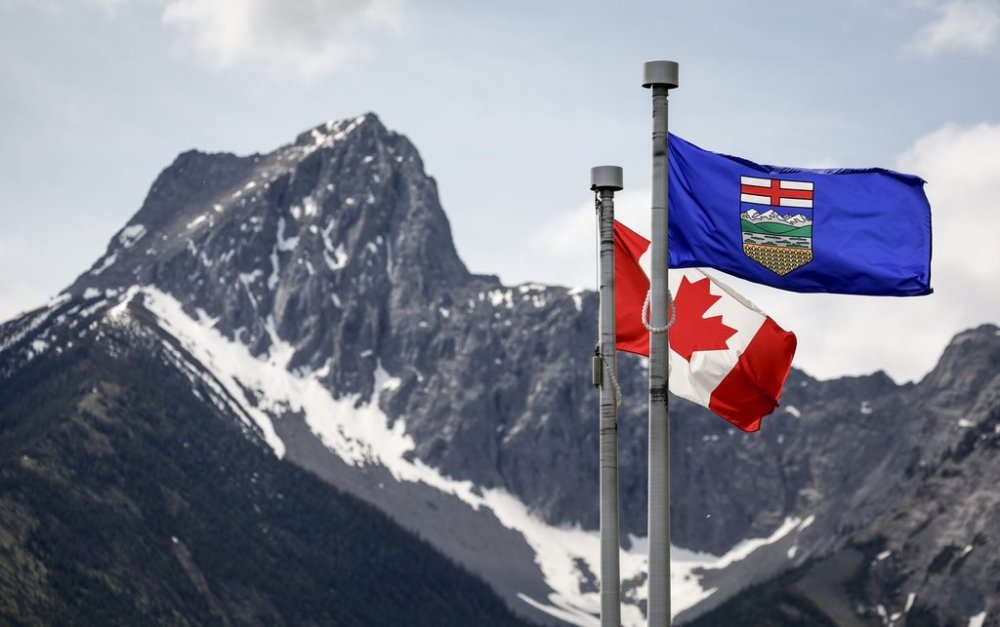 A Canada flag, left, and an Alberta flag flap in the breeze with Wedge Mountain in the background in Kananaskis, Alta., on Monday, June 2, 2025. THE CANADIAN PRESS/Jeff McIntosh