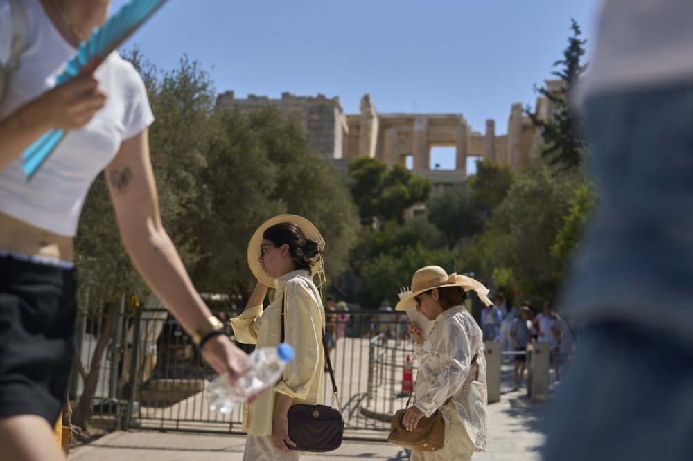Tourist walk outside the Acropolis of Athens, on Monday, July 7, 2025 while authorities in Greece have imposed mandatory work stoppages in parts of the country where temperatures are expected to exceed 40 degrees Celsius (104 Fahrenheit) (AP Photo/Petros Giannakouris)