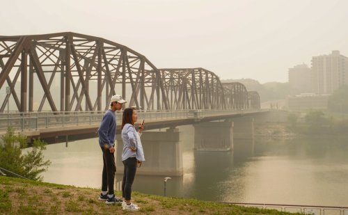 Two people stand as the South Saskatchewan River is enveloped by forest fire smoke in Saskatoon, on Sunday, Sept. 3, 2023. Saskatchewan public safety officials say they are anticipating an average wildfire season with a cooler spring and hotter summer. THE CANADIAN PRESS/Heywood Yu