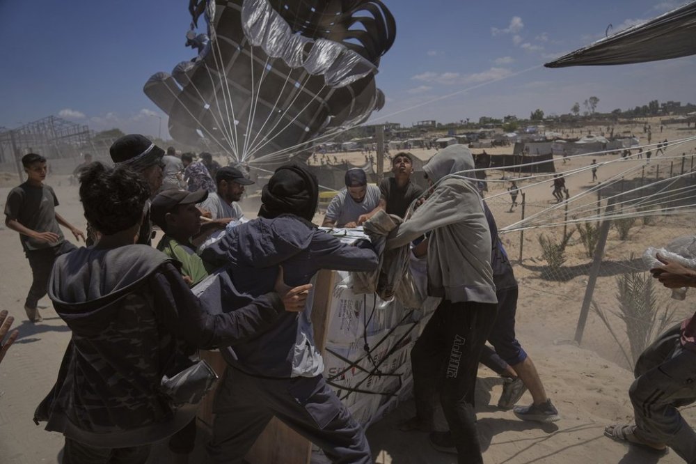 Palestinians rush to collect humanitarian aid airdropped by parachutes into Deir al-Balah, central Gaza Strip, Tuesday, Aug. 5, 2025. (AP Photo/Abdel Kareem Hana)