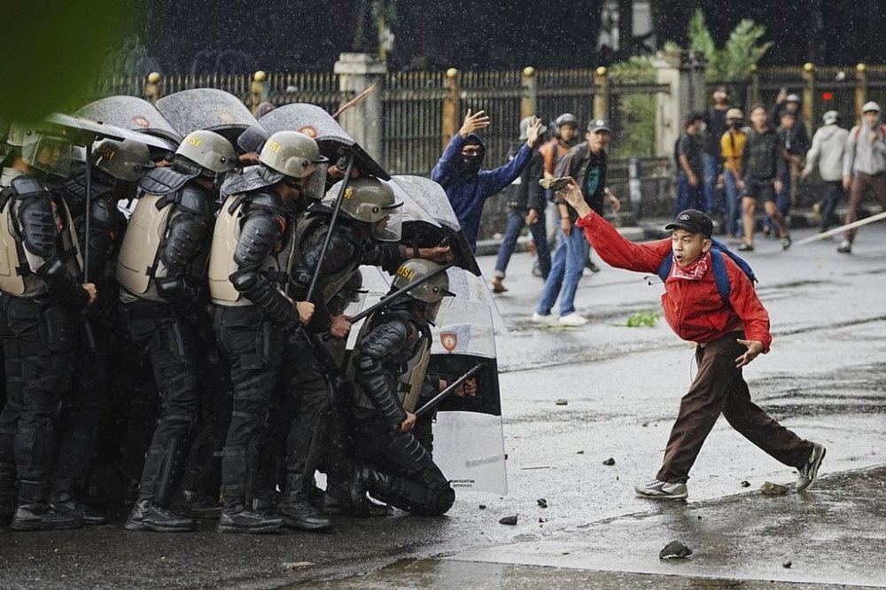 A demonstrator throws a rock at police during a protest against lavish allowances given to parliament members in Jakarta, Indonesia, Aug. 28, 2025. (AP Photo/Achmad Ibrahim)