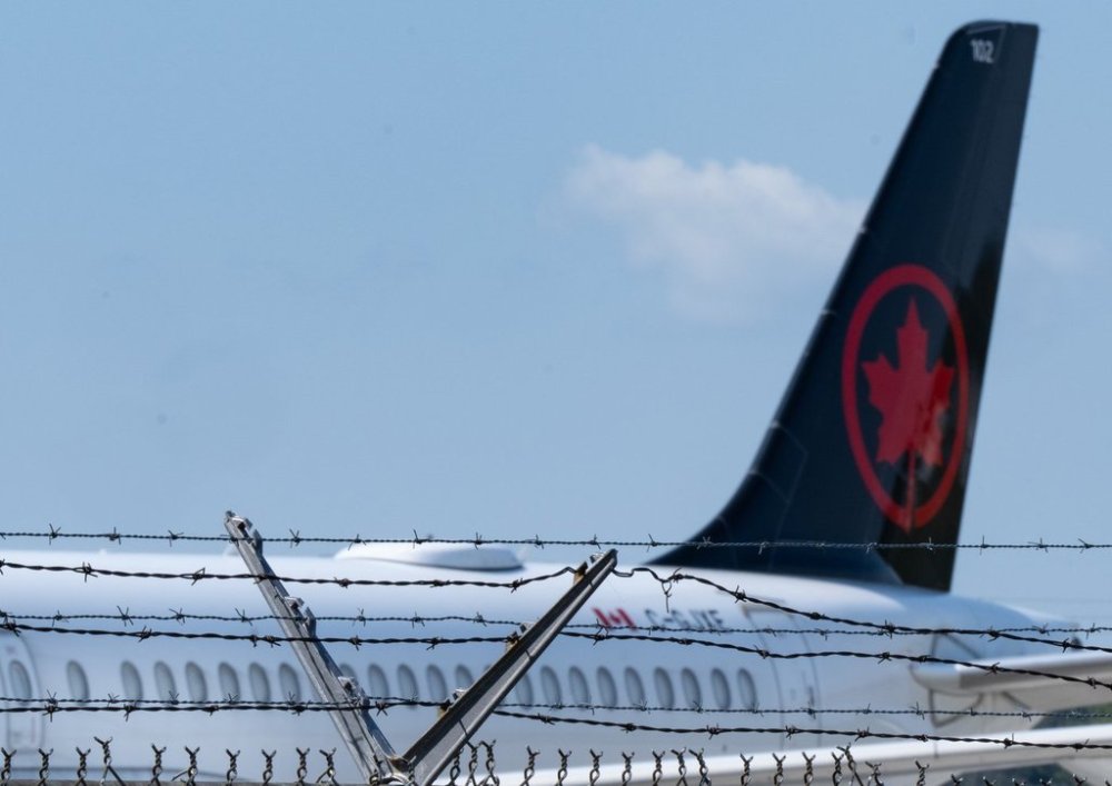 An Air Canada plane is seen behind a fence at their hangar at Montreal-Pierre Elliott Trudeau International Airport in Montreal, Friday, Sept. 13, 2024. THE CANADIAN PRESS/Christinne Muschi