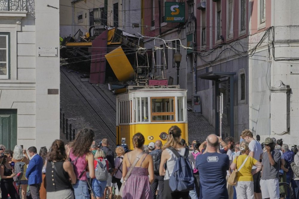 People look at a tourist streetcar that derailed and crashed in Lisbon, Portugal, Thursday, Sept. 4, 2025. (AP Photo/Armando Franca)
