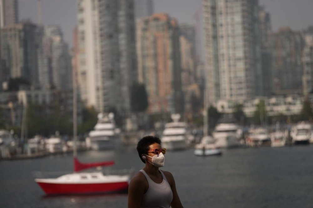 A pedestrian wears a mask while walking on the False Creek seawall as smoke from wildfires burning in B.C. and the U.S. hangs in the air, in Vancouver, B.C., Wednesday, Sept. 3, 2025. Environment Canada has issued an air quality warning in Metro Vancouver and the Fraser Valley due to the smoke that is expected to last for a few days or until there is a change in weather. THE CANADIAN PRESS/Darryl Dyck