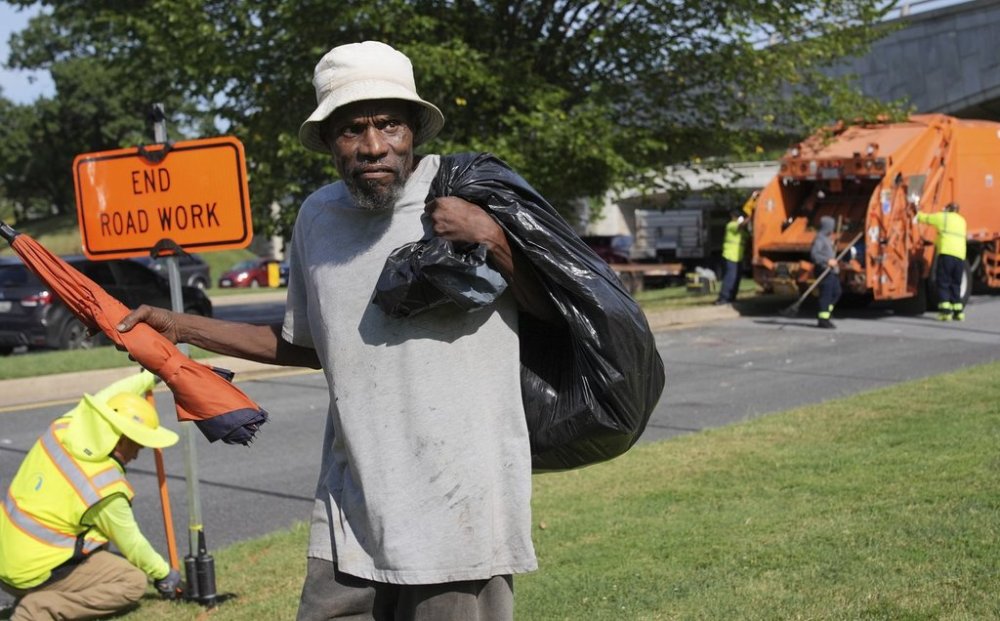 George, 67, walks away with what's left of his belongings, after the city put his mattress and other belongings in a dump truck, Thursday, Aug. 14, 2025, in Washington. (AP Photo/Jacquelyn Martin)