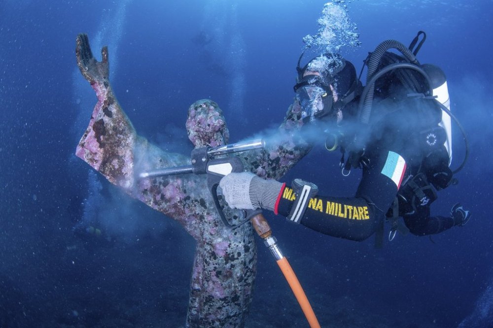 A scuba diver of the Italian Navy cleans the bronze statue of Jesus Christ located in the Mediterranean Sea, off San Fruttuoso, between Camogli and Portofino on the Italian Riviera, Tuesday, Aug. 19, 2025. (Superintendency of Archaeology, Fine Arts and Landscape for Liguria Via AP)