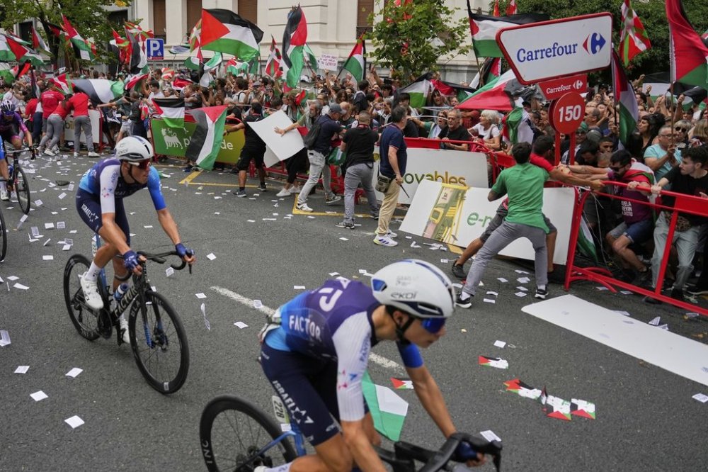 Riders of the Israel Premier Tech team compete as people holding Palestinian flags try to disrupt the eleventh stage of the Spanish Vuelta cycling race, from Bilbao to Bilbao, Spain, Wednesday, Sept. 3, 2025. (AP Photo/Miguel Oses)