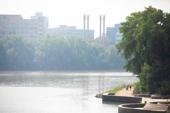 Smoke hangs over the Red River as people walk the River Trail at The Forks on Thursday. (Mikaela MacKenzie / Free Press files)