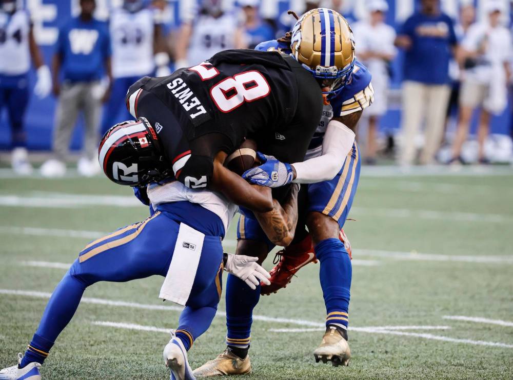 John Woods / THE CANADIAN PRESS
Ottawa Redblacks’ Geno Lewis gets tackled by Winnipeg Blue Bombers’ Trey Vaval and Michael Griffin in the first half.