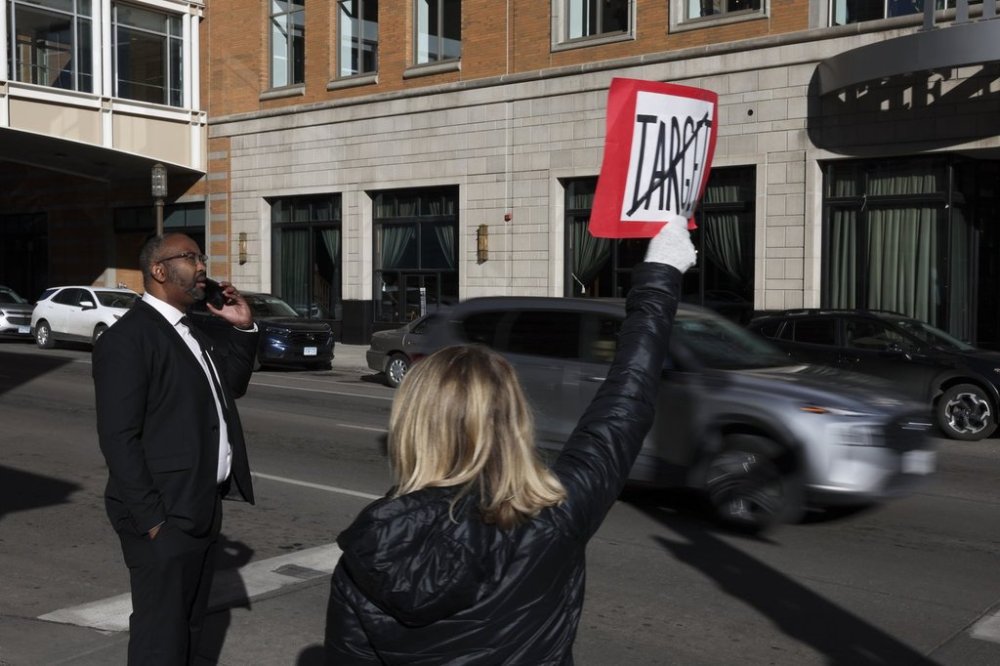 FILE - Becky Dankowski, center, of Minneapolis, holds an anti-Target sign to traffic while Jaylani Hussein, executive director of the Minnesota chapter of the Council on American-Islamic Relations, takes a phone call before a news conference outside Target Corporation's headquarters, Jan. 30, 2025, in Minneapolis, Minn. (AP Photo/Ellen Schmidt, file)