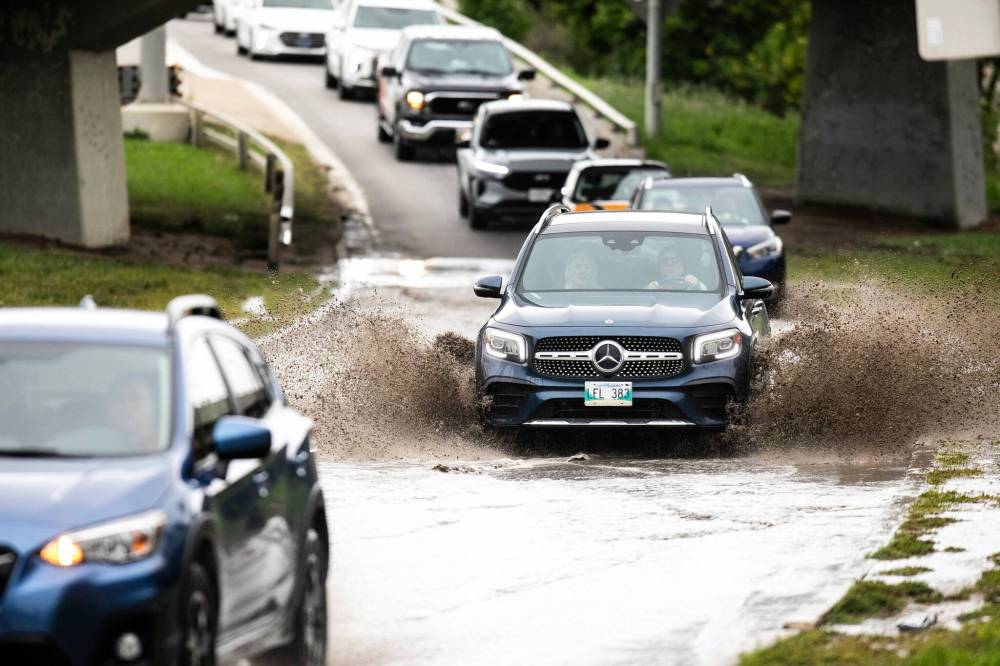 MIKAELA MACKENZIE / FREE PRESS
Cars drive through a large puddle of water headed south off the St. James Bridge and onto Academy Road on Thursday.