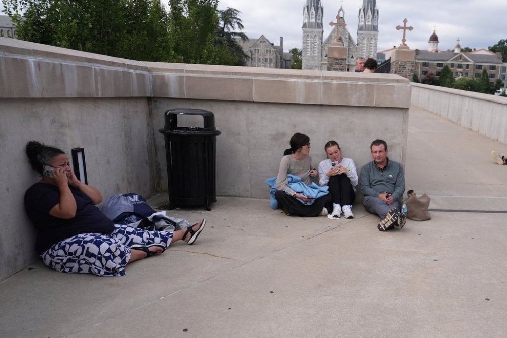 Police shelter behind a wall at the Villanova University campus where an active shooter was reported Thursday, Aug. 21, 2025, in Villanova, Pa. (AP Photo/Matt Slocum)
