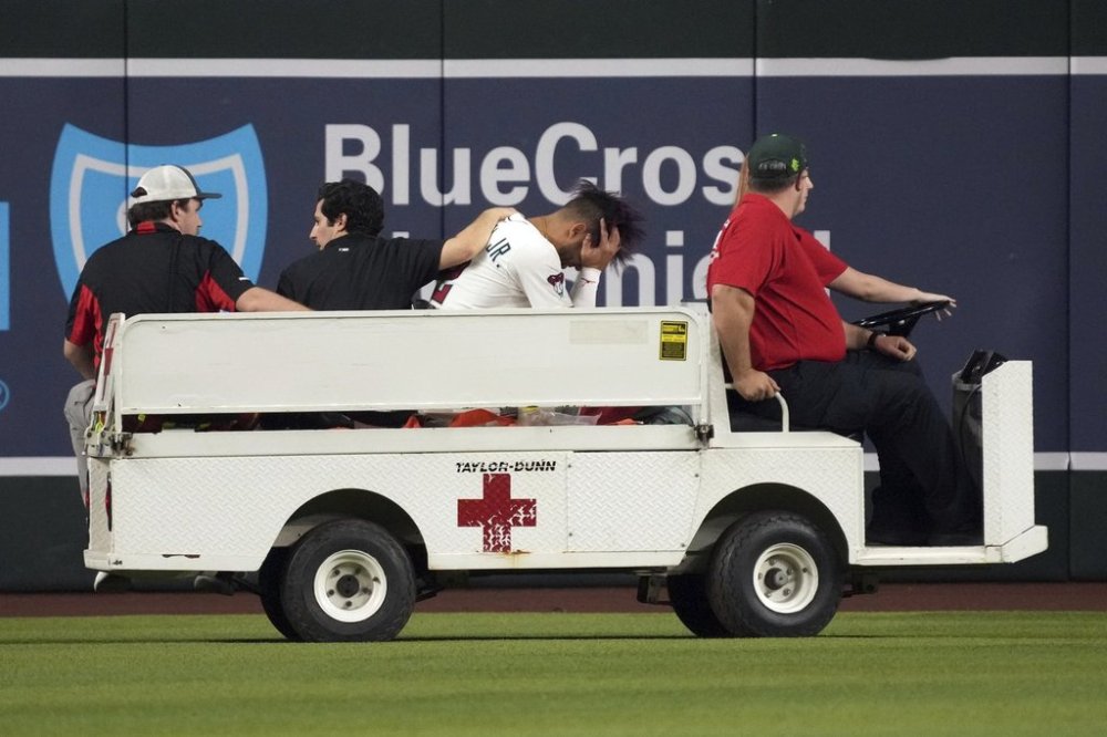 Arizona Diamondbacks' Lourdes Gurriel Jr., third from left, is taken out on a cart after diving for a ball hit by Texas Rangers' Rowdy Tellez in the sixth inning of a baseball game, Monday, Sept. 1, 2025, in Phoenix. (AP Photo/Rick Scuteri)
