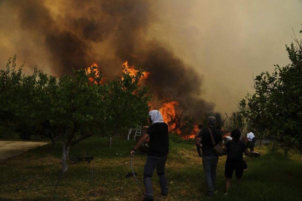 People try to control a wildfire in Vounteni, on the outskirts of Patras, western Greece, Wednesday, Aug. 13, 2025. (AP Photo/Thanassis Stavrakis)
