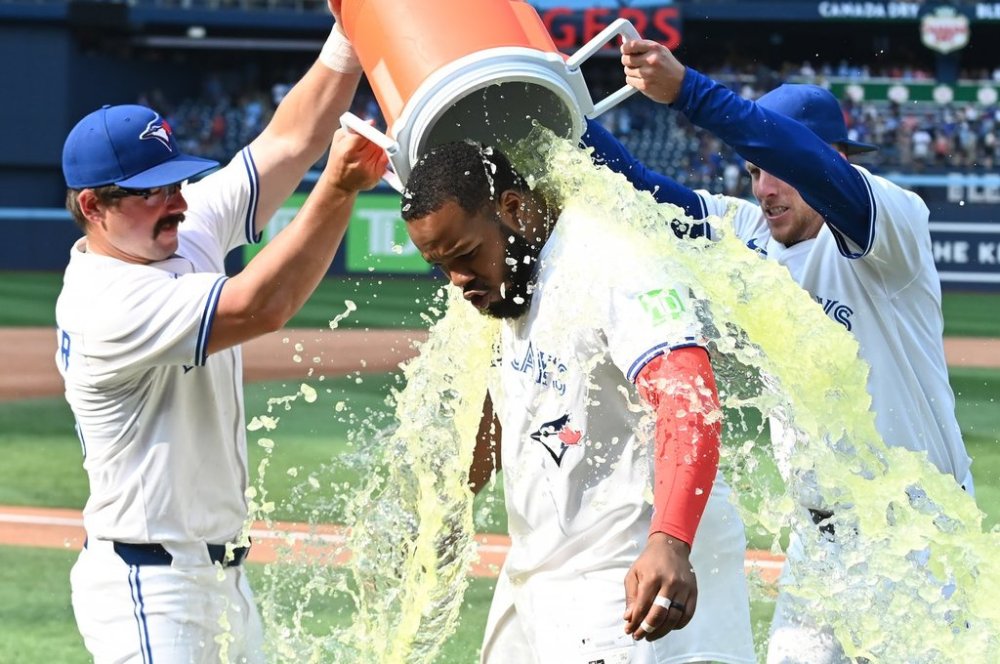 Toronto Blue Jays' Davis Schneider, left and Myles Straw douse Vladimir Guerrero Jr. after defeating the Chicago Cubs in MLB baseball game action in Toronto on Thursday, August 14, 2025. THE CANADIAN PRESS/Jon Blacker