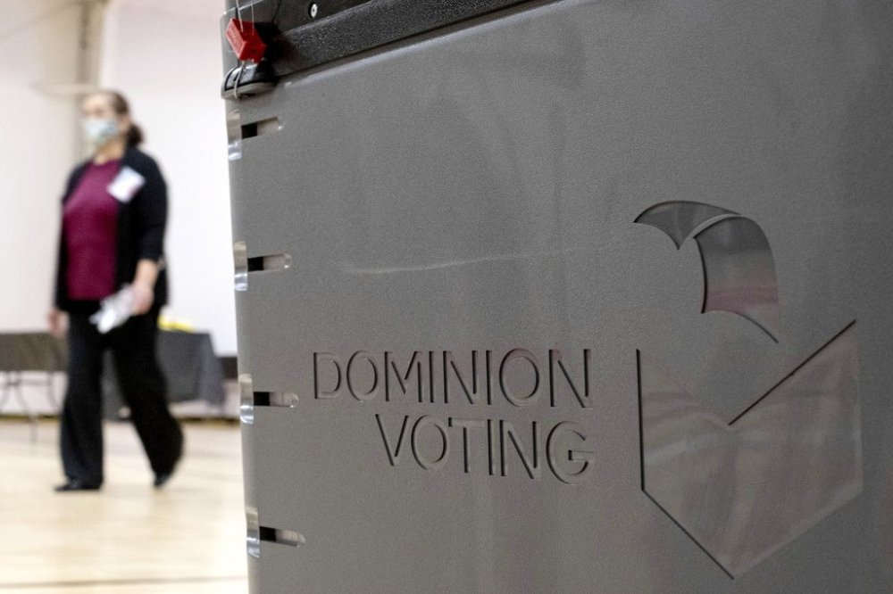 FILE - A worker passes a Dominion Voting ballot scanner while setting up a polling location at an elementary school in Gwinnett County, Ga., outside of Atlanta on Jan. 4, 2021. (AP Photo/Ben Gray, File)