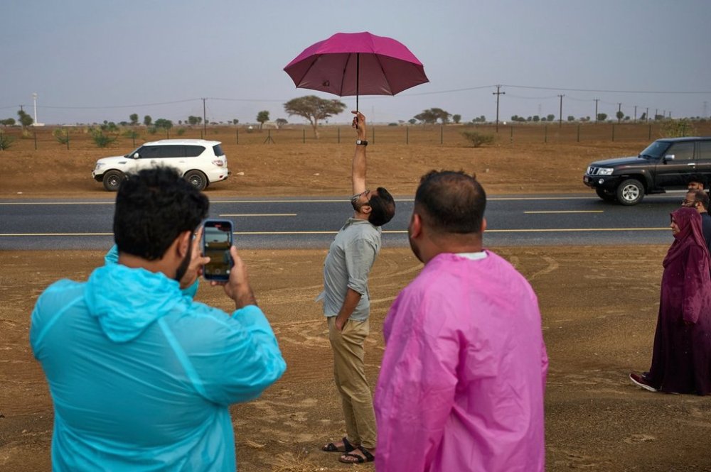 People stand in the rain as they chase rain showers at Fujairah, United Arab Emirates, Saturday, Aug. 30, 2025. (AP Photo/Fatima Shbair)