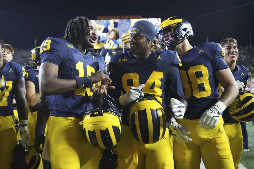 Michigan quarterback Bryce Underwood, left, speaks with edge Nate Marshall, center, and wide receiver Bryce Wilcox, front right, after their team's win over New Mexico in an NCAA college football game, Saturday, Aug. 30, 2025, in Ann Arbor, Mich. (AP Photo/Ryan Sun)