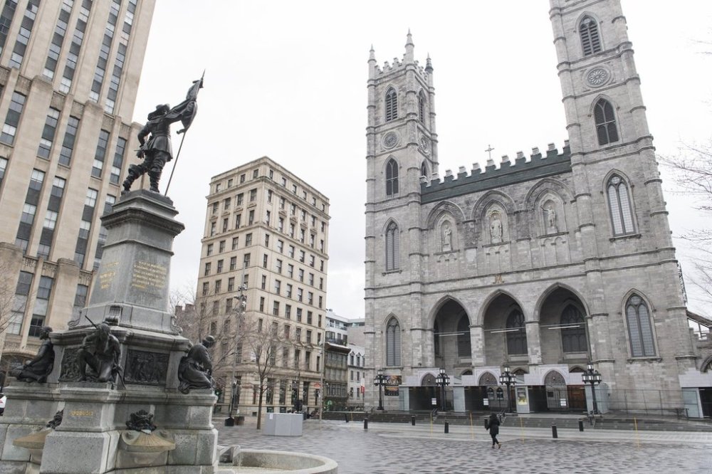 A woman walks by Notre-Dame Basilica in Montreal, Friday, April 10, 2020. A video that shows a fire at a different church in Trois-Rivières, Que. from last October was recenty shared on social media by accounts who falsely claimed it showed the Notre-Dame Basilica in flames. THE CANADIAN PRESS/Graham Hughes