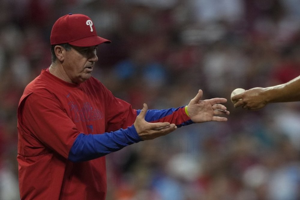 Philadelphia Phillies manager Rob Thomson, left, takes the ball from pitcher Ranger Suárez during pitching change in the sixth inning of a baseball game against the Cincinnati Reds Tuesday, Aug. 12, 2025, in Cincinnati. (AP Photo/Carolyn Kaster)