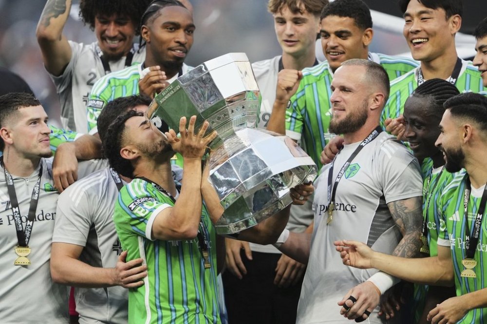 Seattle Sounders midfielder Cristian Roldan kisses the Leagues Cup trophy as goalkeeper Stefan Frei, in grey, looks on while the team celebrates beating Inter Miami in the Leagues Cup final soccer match Sunday, Aug. 31, 2025, in Seattle. (AP Photo/Lindsey Wasson)