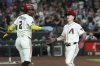Arizona Diamondbacks' Geraldo Perdomo (2) and Corbin Carroll celebrate their runs scored against the Cleveland Guardians during the seventh inning of a baseball game Tuesday, Aug. 19, 2025, in Phoenix. (AP Photo/Ross D. Franklin)
