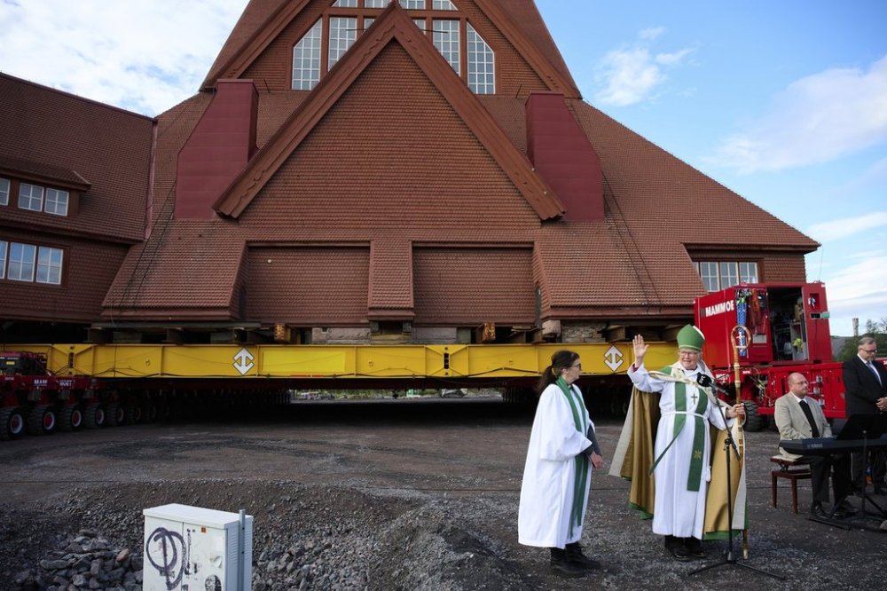 FILE - Vicar Lena Tjarnberg, left, and Bishop Asa Nystrom bless the Kiruna Church, a Sami style wooden Swedish Lutheran church, called Kiruna Kyrka in Swedish, in Kiruna, Sweden, Tuesday, Aug. 19, 2025, shortly before the start of its move along a 5-kilometer (3-mile) route east to a new city center as part of the town's relocation. (AP Photo/Malin Haarala, File)