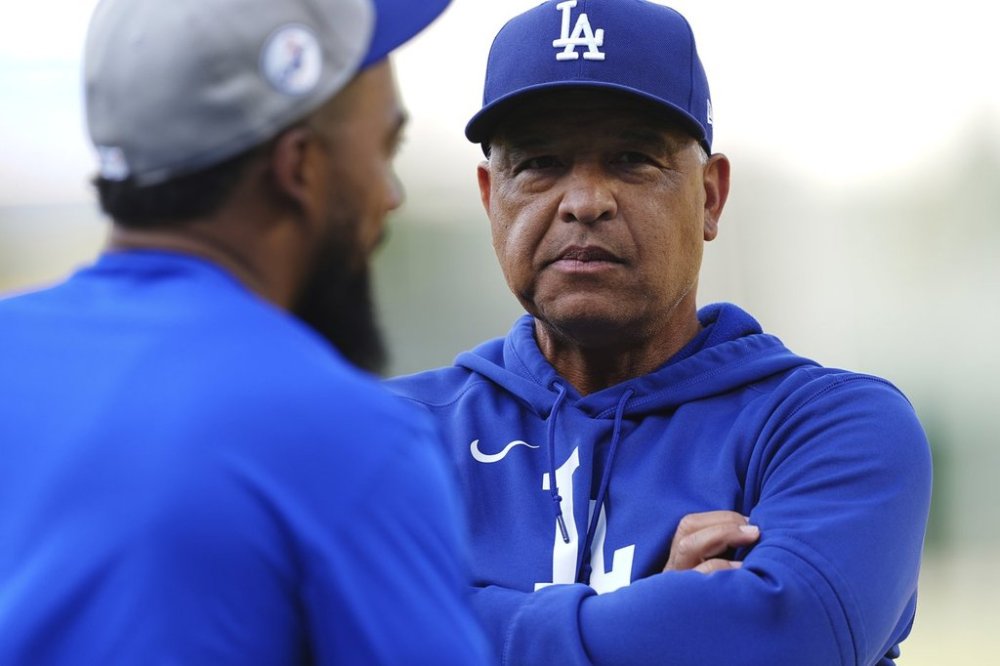 Los Angeles Dodgers manager Dave Roberts, back, talks with right fielder Teoscar Hernández as he warms up before a baseball game against the Colorado Rockies Wednesday, Aug. 20, 2025, in Denver. (AP Photo/David Zalubowski)