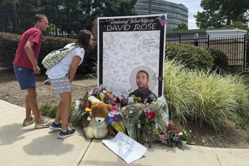 People leave flowers Monday, Aug. 11, 2025, at a makeshift memorial in honor of David Rose, the officer who was killed in the shooting at the U.S. Centers for Disease Control and Prevention headquarters in Atlanta. (AP Photo/Charlotte Kramon)
