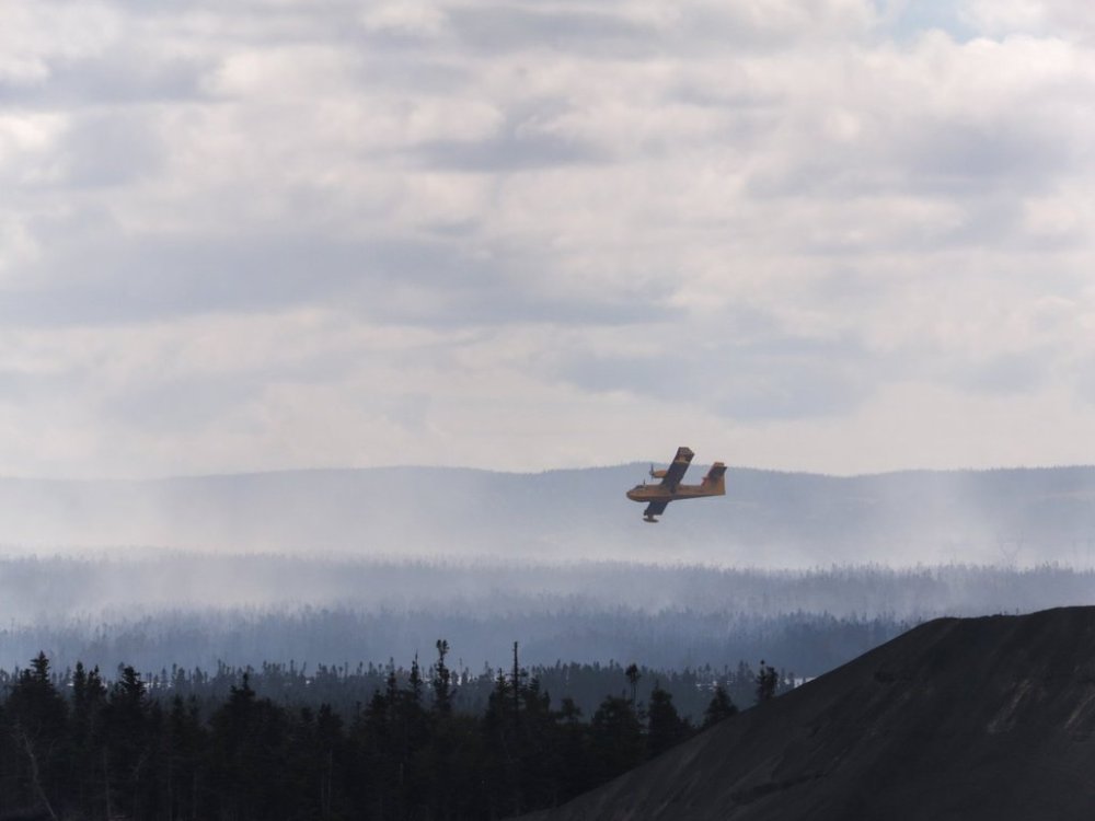 A water bomber flies over a wildfire in the Paddy's Pond area just outside St. John's, N.L., on Wednesday, Aug. 13, 2025. THE CANADIAN PRESS/Elling Lien