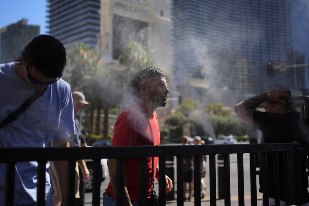 FILE - People cool off in misters along the Las Vegas Strip, Sunday, July 7, 2024, in Las Vegas. (AP Photo/John Locher, File)
