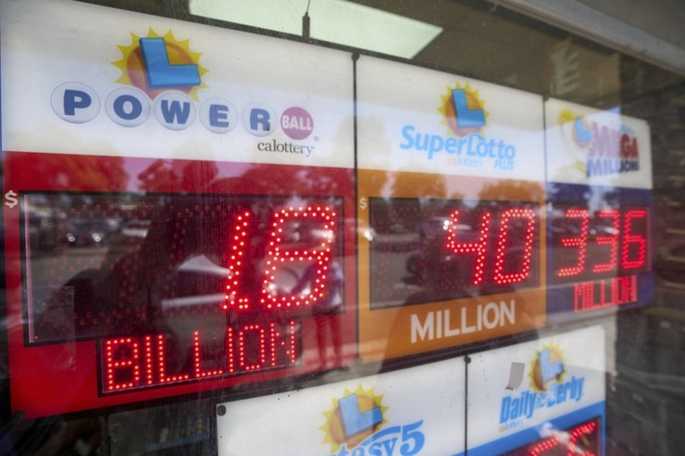 An electronic sign reads $1.8 billion as crowds wait in line to buy lottery tickets at the Bluebird Liquor store in Hawthorne, Calif., on Friday, Sept. 5, 2025. (AP Photo/Damian Dovarganes)