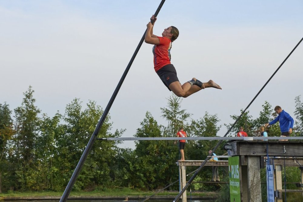 A female jumps towards the carbon pole to cross a body of water during a Fierljeppen competition in Kockengen, Netherlands, Wednesday, Aug. 27, 2025. (AP Photo/Peter Dejong)