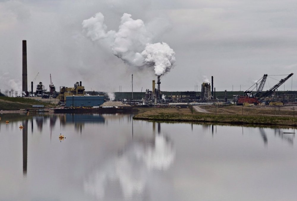 The Syncrude oilsands extraction facility is reflected in a tailings pond near Fort McMurray, Alta., on Sunday, June 1, 2014. THE CANADIAN PRESS/Jason Franson