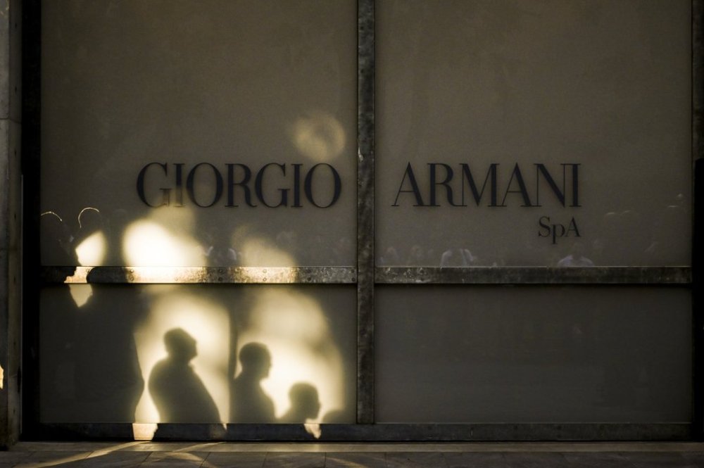 Staff of Giorgio Armani Spa gather outside the Armani/Teatro in Milan, northern Italy, as they wait for the hearse with the casket of designer Giorgio Armani, who died Thursday at age 91, Sunday, Sept. 7, 2025. (AP Photo/Nicola Marfisi)