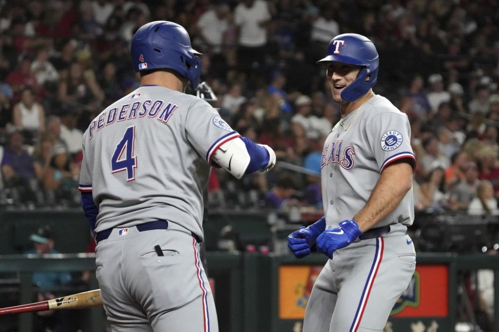 Texas Rangers' Wyatt Langford, right, celebrates with Joc Pederson (4) after hitting a solo home run against the Arizona Diamondbacks in the sixth inning of a baseball game, Monday, Sept. 1, 2025, in Phoenix. (AP Photo/Rick Scuteri)