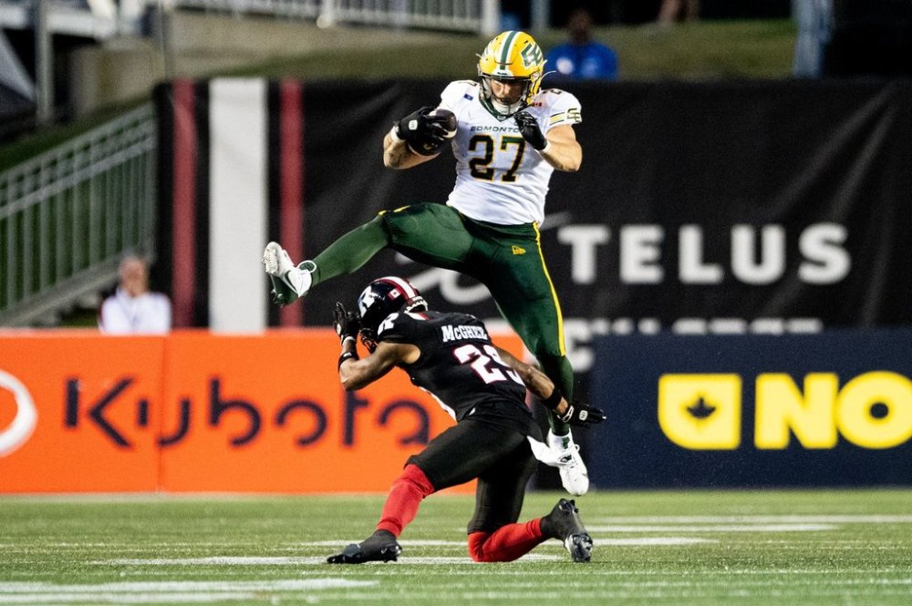 Edmonton Elks running back Tanner Green (27) leaps over Ottawa Redblacks defensive back Alijah McGhee (29) as he runs with the ball during first half CFL action in Ottawa, on Friday, Aug. 22, 2025. THE CANADIAN PRESS/Spencer Colby
