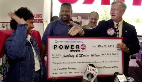FILE - South Carolina Education Lottery Director, Ernie Passailaigue , right, extends his hand to Monica and Anthony Wilson, of Charlotte, N.C., as he presents them with a check for their Powerball winnings Thursday May 29, 2003, at Red Rocket Fireworks in Fort Mill, S.C. (AP Photo/Mary Ann Chastain, File)