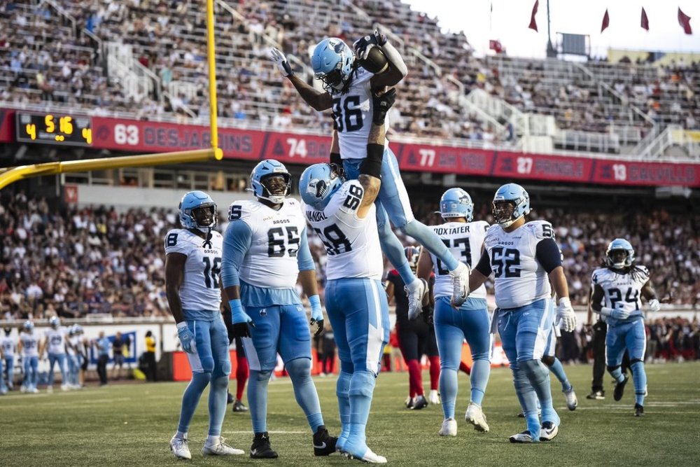Toronto Argonauts' Damonte Coxie (86) celebrates with Anthony Vandal (58) after scoring during first half CFL action against the Montreal Alouettes in Montreal on Thursday, July 17, 2025. THE CANADIAN PRESS/Christopher Katsarov