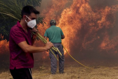 Residents battle a fire advancing toward Rebordondo village, near Ourense, in northwestern Spain, on Monday, Aug. 18, 2025. (AP Photo/Pablo Garcia)