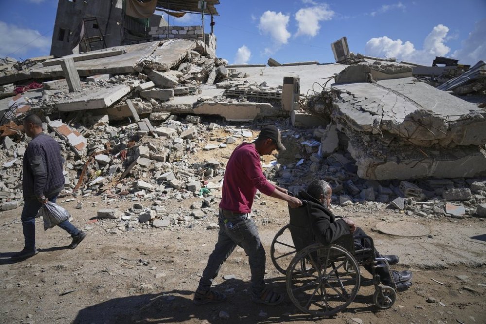 FILE - Wasem Attiya pushes his father, Mohamed, 54, in a wheelchair as they head to Shifa hospital in Gaza City for a dialysis session, Monday, April 14, 2025. (AP Photo/Jehad Alshrafi, File)
