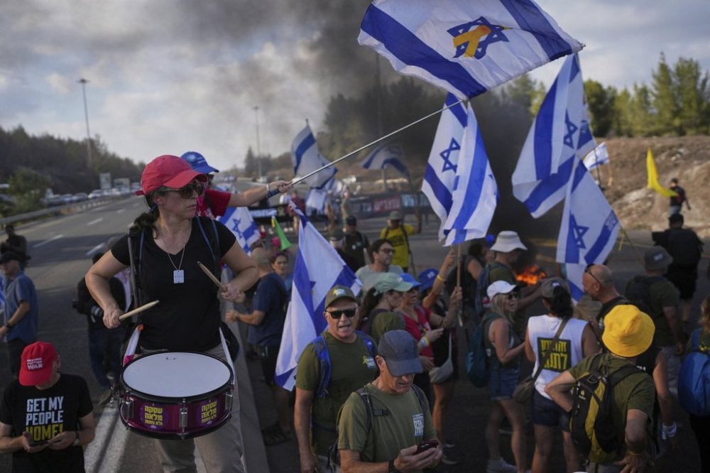 Demonstrators block a road during a protest demanding the immediate release of hostages held by Hamas and calling for the Israeli government to reverse its decision to take over Gaza City and other areas in the Gaza Strip, near Jerusalem, Israel, Sunday, Aug. 17, 2025. (AP Photo/Ohad Zwigenberg)