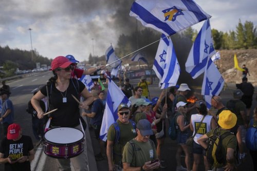 Demonstrators block a road during a protest demanding the immediate release of hostages held by Hamas and calling for the Israeli government to reverse its decision to take over Gaza City and other areas in the Gaza Strip, near Jerusalem, Israel, Sunday, Aug. 17, 2025. (AP Photo/Ohad Zwigenberg)