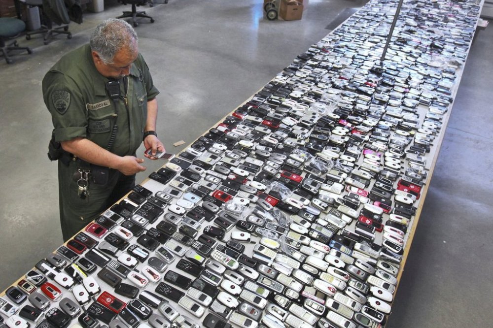 FILE - Correctional Officer Jose Sandoval inspects one of the more than 2,000 cell phones confiscated from inmates at California State Prison, Solano in Vacaville, Calif., April 10, 2009. (AP Photo/Rich Pedroncelli, File)