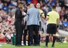 Referee Anthony Taylor speaks with Liverpool manager Arne Slot and Bournemouth manager Andoni Iraola after Bournemouth's Antoine Semenyo, not pictured, informed the referee of a possible racial comment from the crowd during the English Premier League soccer match between Liverpool and Bournemouth at Anfield, Liverpool, England, Friday Aug. 15, 2025. (Peter Byrne/PA via AP)