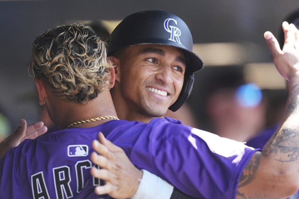 Colorado Rockies' Orlando Arcia, front, congratulates Ryan Ritter after he scored on a single hit by Mickey Moniak off Arizona Diamondbacks relief pitcher Jake Woodford in the seventh inning of a baseball game Sunday, Aug. 17, 2025, in Denver. (AP Photo/David Zalubowski)