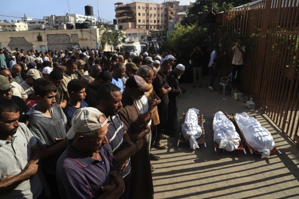Mourners pray over the bodies of three Palestinians, killed along with others in Israeli strikes, during their funeral outside Nasser Hospital in Khan Younis, southern Gaza Strip, Saturday, Aug. 23, 2025. (AP Photo/Mariam Dagga)