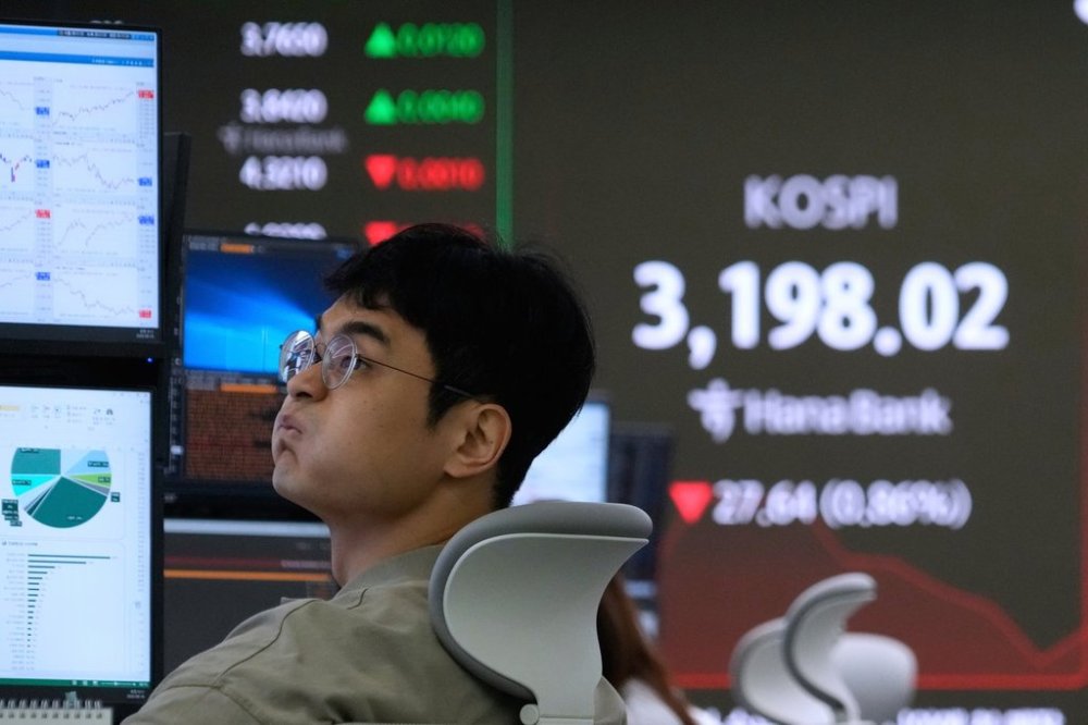 A currency trader watches monitors near a screen showing the Korea Composite Stock Price Index (KOSPI) at the foreign exchange dealing room of the Hana Bank headquarters in Seoul, South Korea, Monday, Aug. 18, 2025. (AP Photo/Ahn Young-joon)